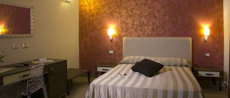A hotel room with a bed, a desk, a chair, and two bedside lamps.