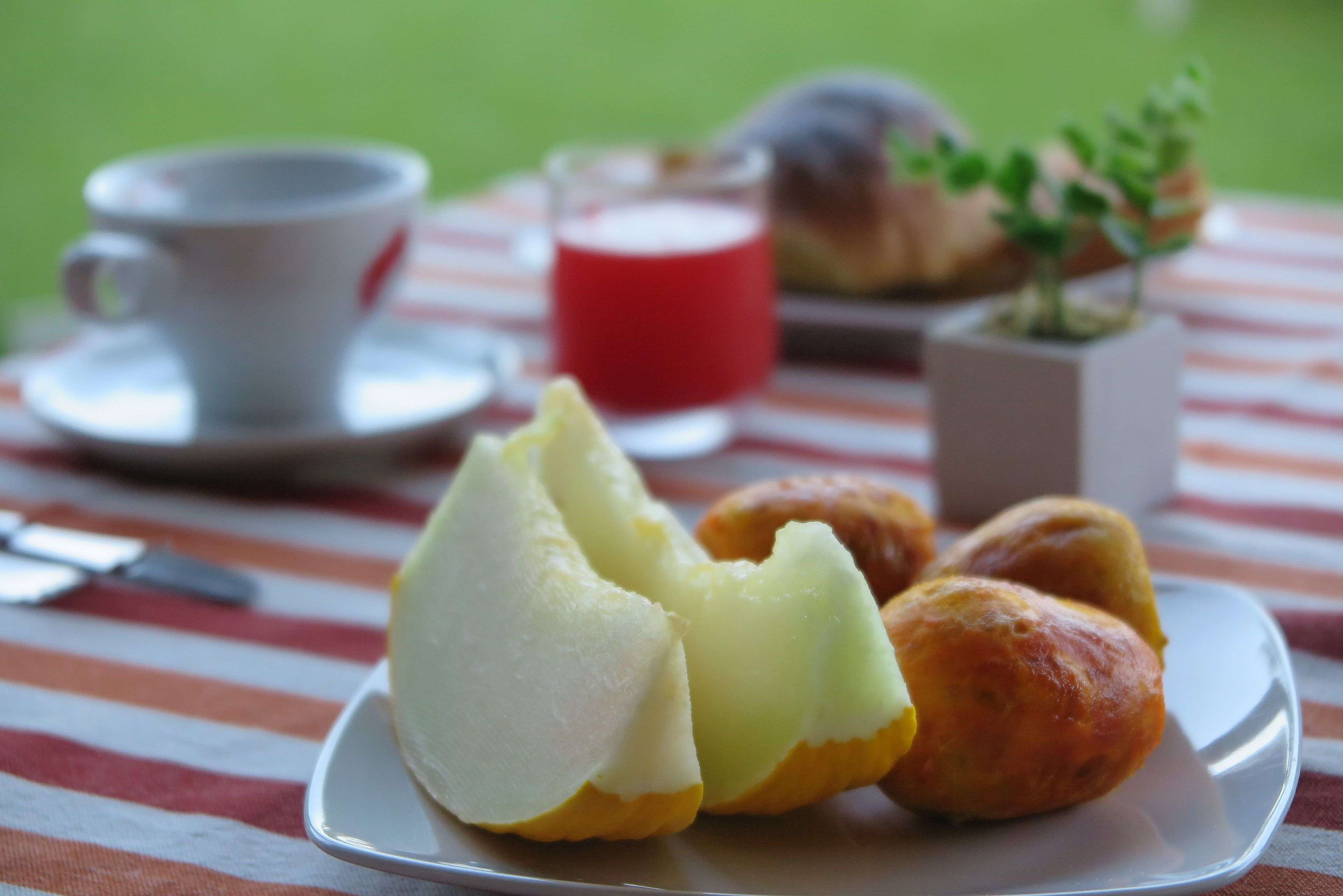 A plate with pastries and a cup of coffee on a striped tablecloth.