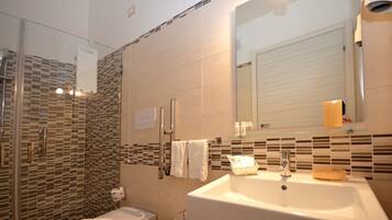 Un baño moderno con cabina de ducha de vidrio, un lavamanos grande y un espejo sobre él.