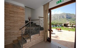 Interior de hotel com uma escadaria, vista para o exterior e paisagem montanhosa.