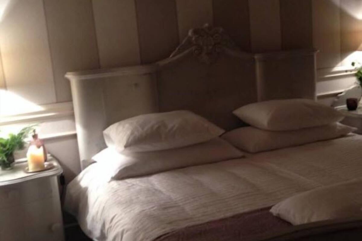 A bedroom with a bed, pillows, a bedside table, and a nightstand.