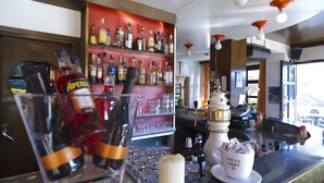 Zona de bar amb calaixos plens de garrafes de licors, gots i una tassa de cafè amb la marca "Pavan Caffe".