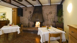 Un restaurant amb parets de maó, una llar de foc i dues taules preparades per dinar.