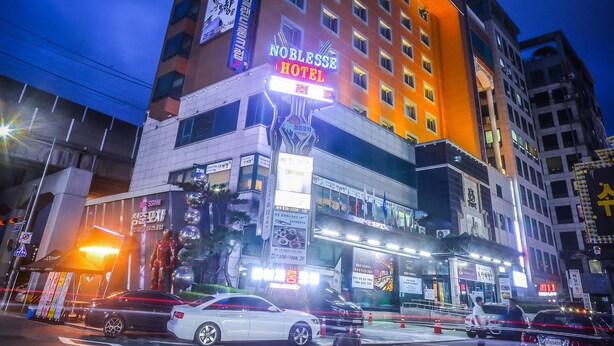 Un hotel de varios pisos con señalización iluminada, incluyendo un cartel llamativo que dice 'NOBLESS HOTEL'.