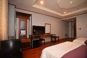 A hotel room with a wooden desk, a television, a bed, and a mirror. - Noblesse Tourist Hotel (Seoul)