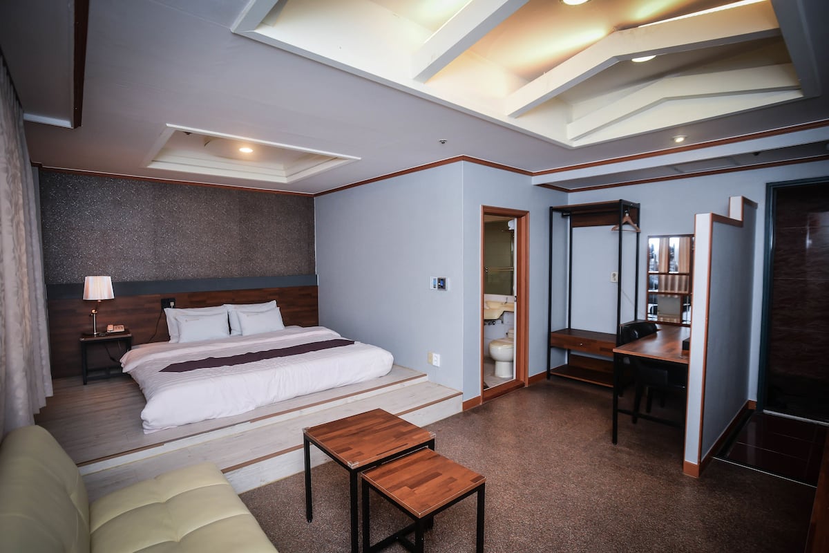 A modern hotel room with a large bed, a desk, and a small table.