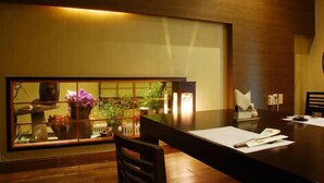 Un comedor con una mesa de madera, sillas y vistas a un jardín a través de un panel de vidrio.