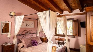 Une chambre à coucher avec un lit à baldaquin, une table de chevet, un bureau et un petit réfrigérateur.