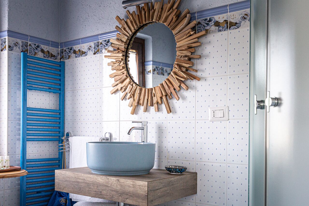 Un baño con un lavamanos azul, un espejo con marco de madera y un toallero azul.
