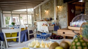 Desayuno con fruta, una estación de café y un fondo de pared de piedra.