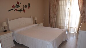 A bedroom with a large bed, two bedside tables with lamps, a nightstand, and a wall-mounted lamp. - Pueblo Quinta (Benalmádena)