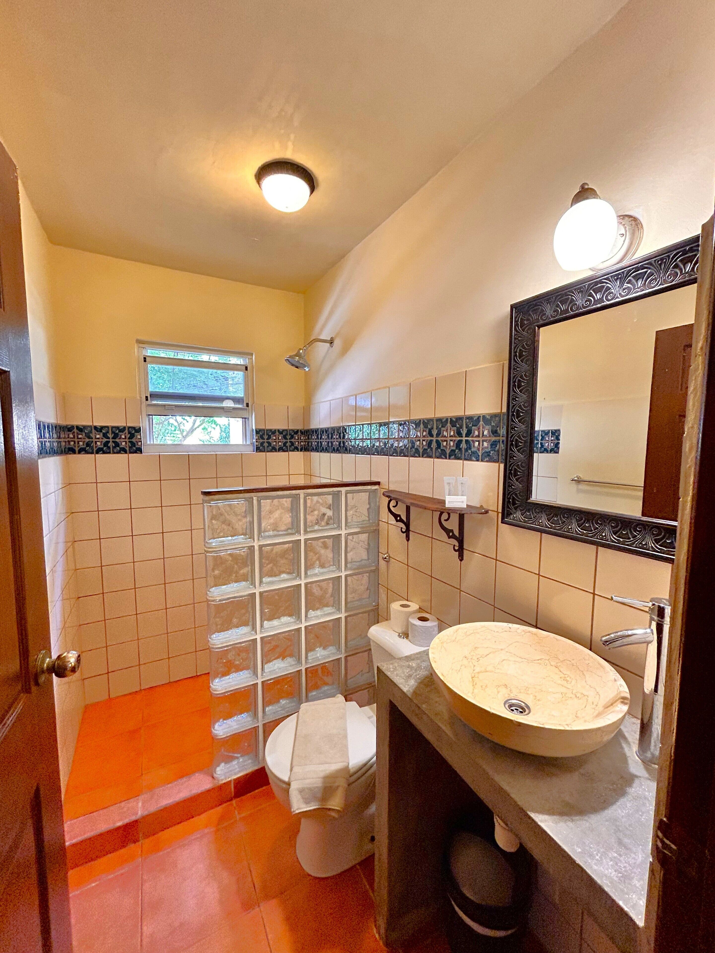 Un baño con inodoro, lavamanos, ducha y ventana.