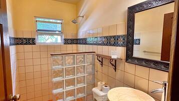 Un baño con inodoro, lavamanos, ducha y ventana.