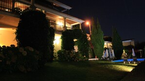 A well-lit residential property at night with a swimming pool, lounge chairs, and a covered patio area. - Casa de Canilhas (Mesão Frio)