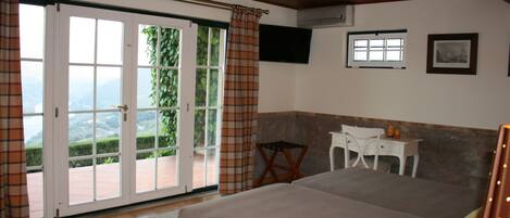 Un dormitorio con cama, escritorio, silla y televisión en la pared.