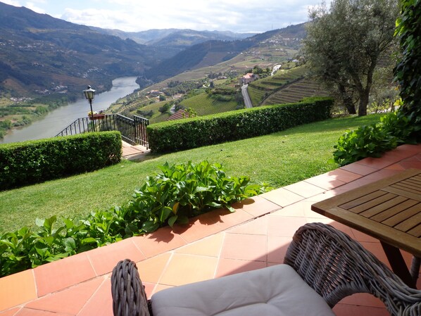 Un patio con una silla de mimbre y vistas a un río y montañas.
