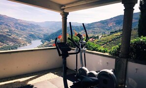 A balcony with exercise equipment overlooking a scenic valley with a river. - Casa de Canilhas (Mesão Frio)