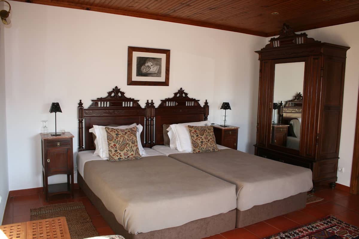 A double bed with a wooden headboard, two bedside tables with lamps, a large mirror, and a framed picture on the wall.