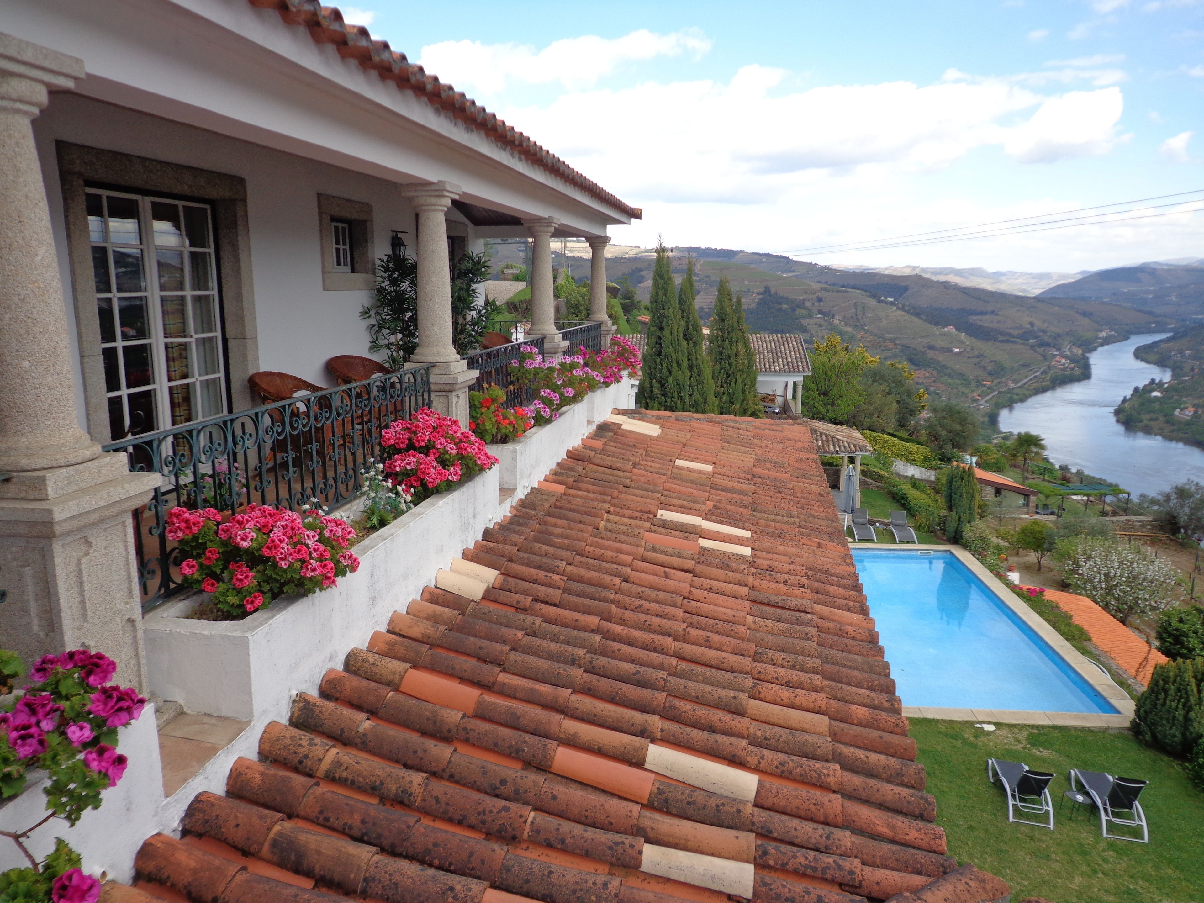 Une villa avec un toit recouvert de tuiles en terre cuite, une piscine et une vue sur une rivière et des montagnes.