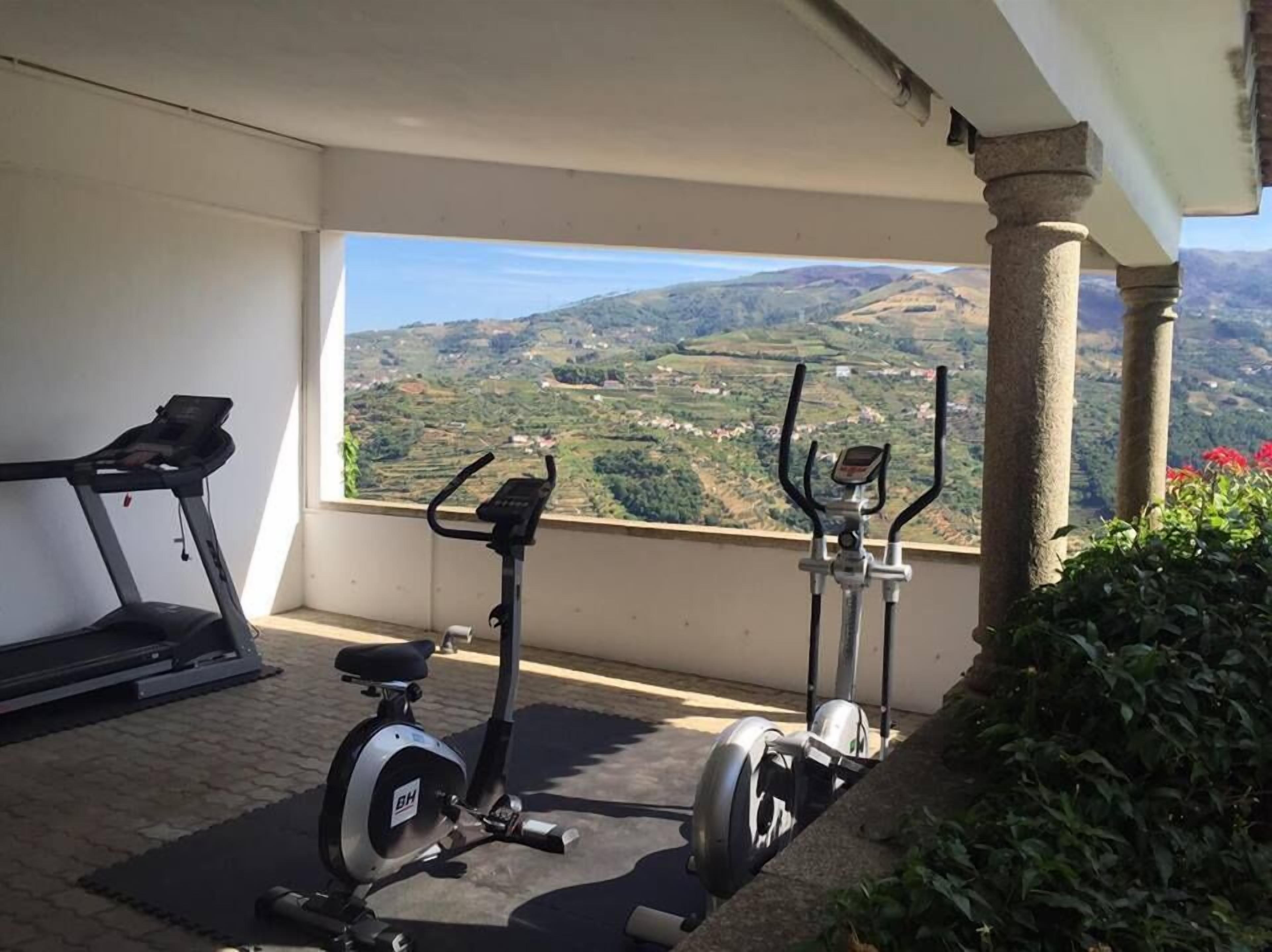 A balcony with exercise equipment and a scenic view of rolling hills.