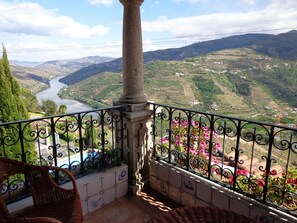 Uma varanda com vista para um rio e uma paisagem montanhosa.