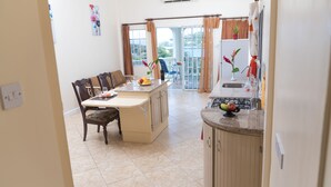 A kitchen with a dining area, a view to the outside, and a small balcony. - Bayside Villa St. Lucia (Castries)