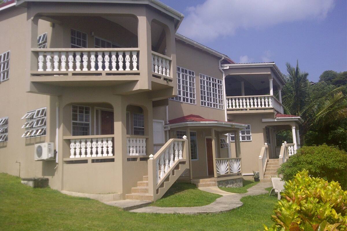A two-story building with a balcony on the second floor, a covered porch, and a staircase leading to the entrance.