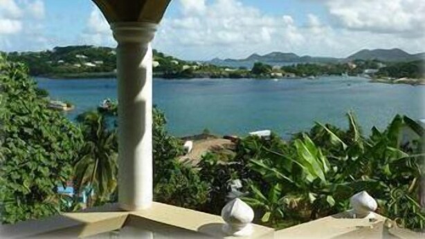 A view of a lake with mountains in the background, a balcony with a white balustrade, and lush greenery. - Bayside Villa St. Lucia (Castries)