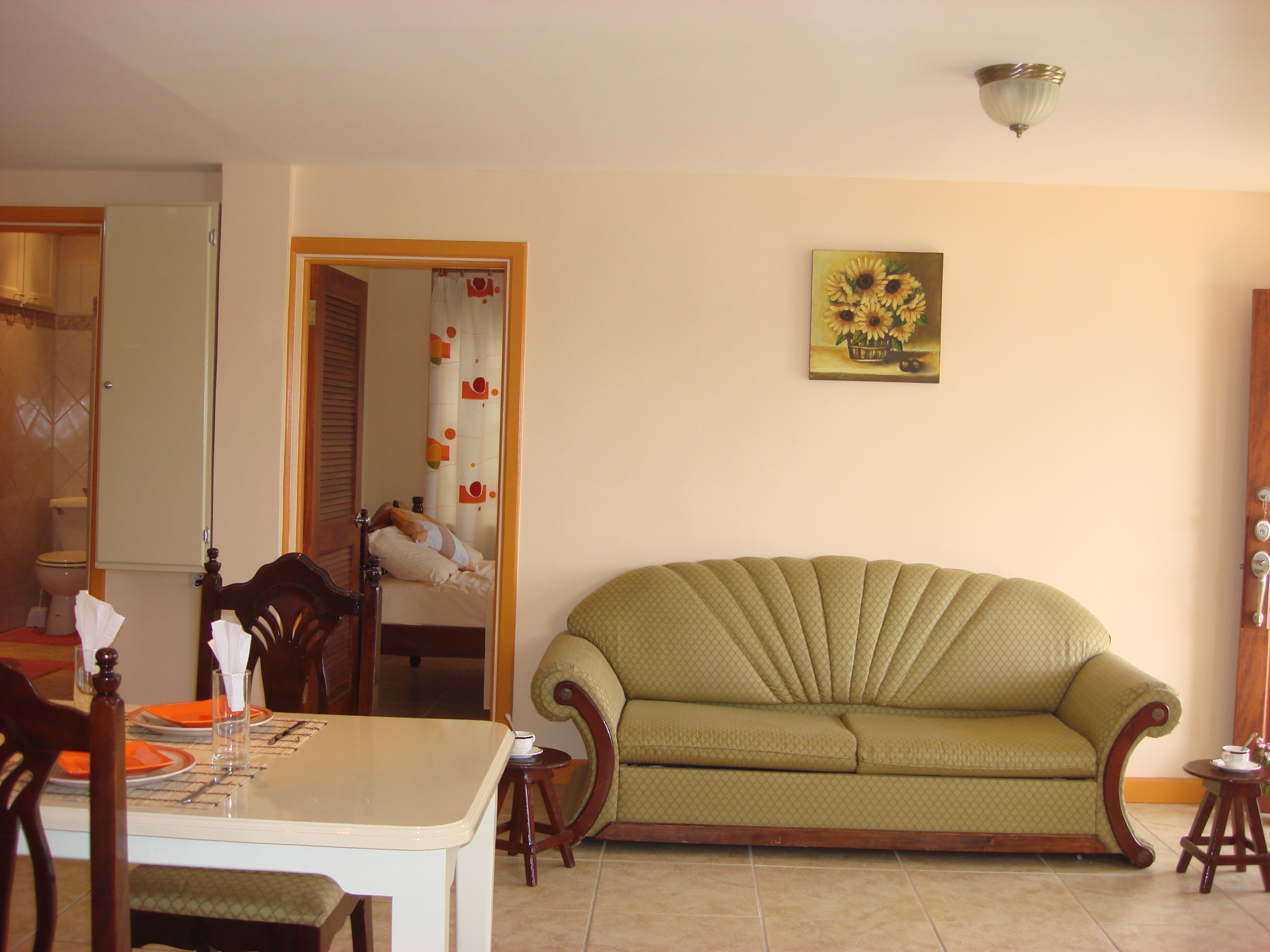 Una sala de estar con un sofá, una mesa de comedor con sillas y un cuadro en la pared.