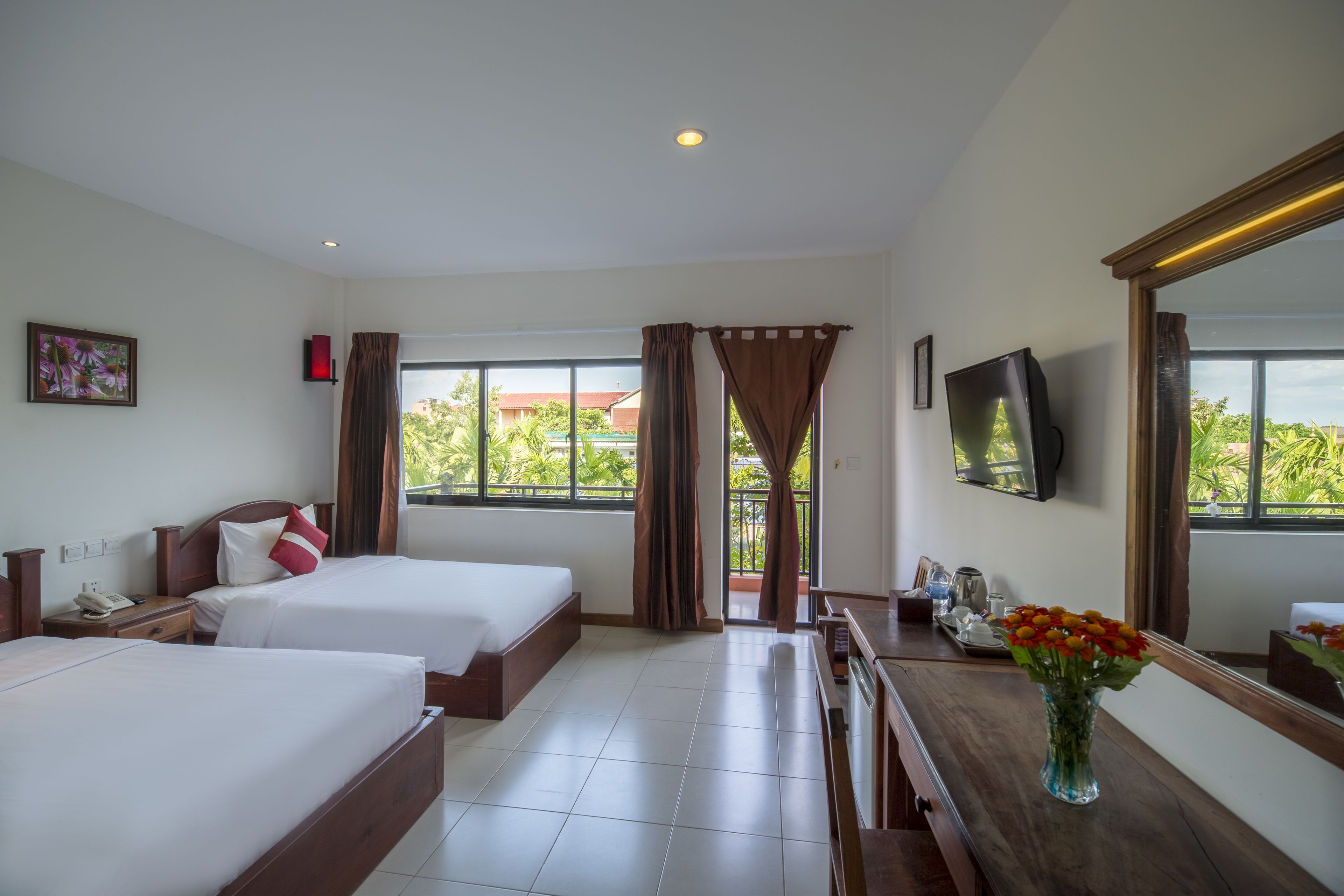A hotel room with two beds, a desk, a TV, and a window with curtains.