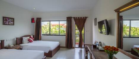 A hotel room with two beds, a desk, a TV, and a window with curtains.