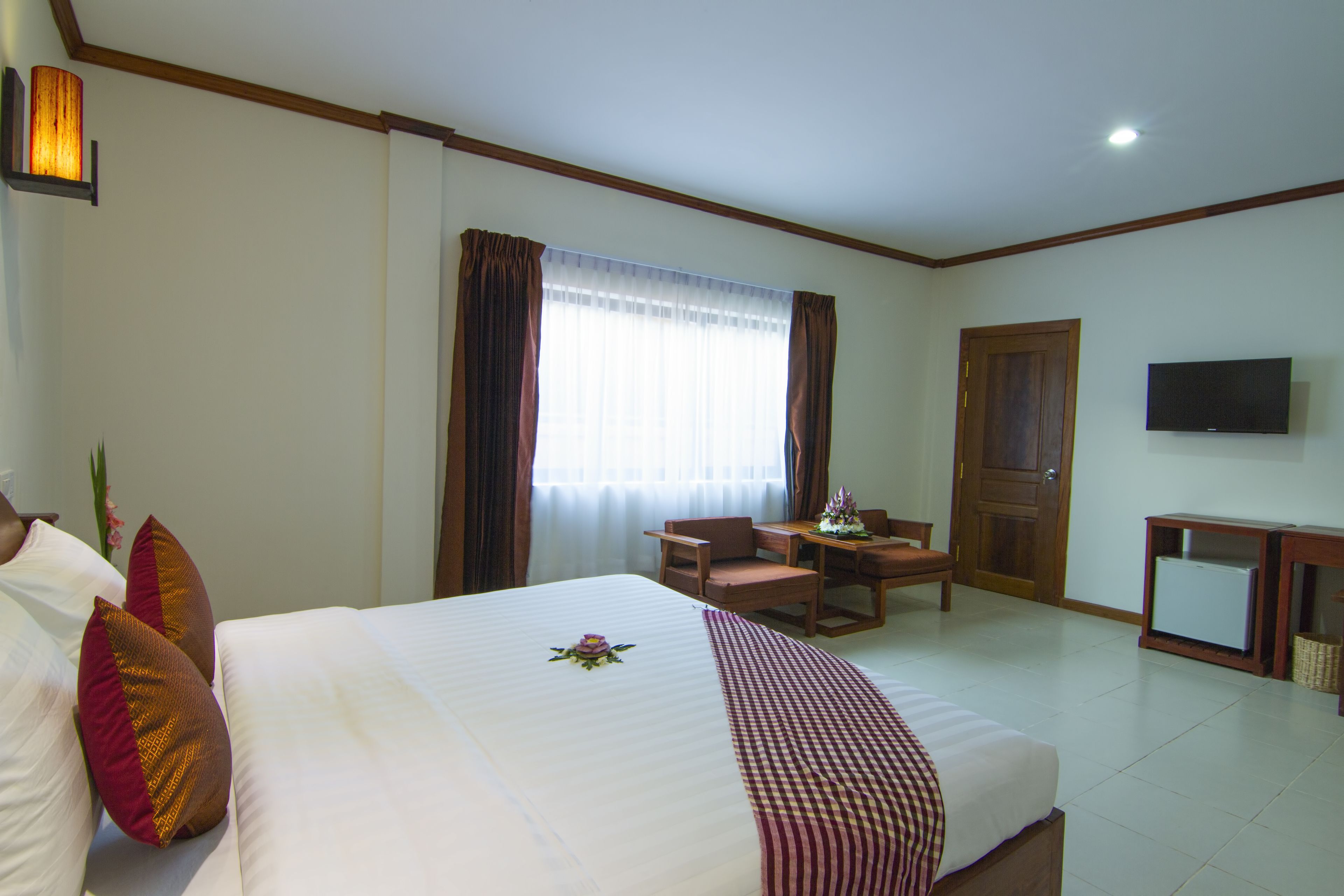 A hotel room with a bed, a desk, a chair, a television, and a door.