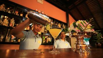 Un cantinero vertiendo una bebida en una copa de martini.