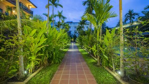 A pathway lined with palm trees leading to a building with multiple balconies. - Kouprey Hotel (Siem Reap)