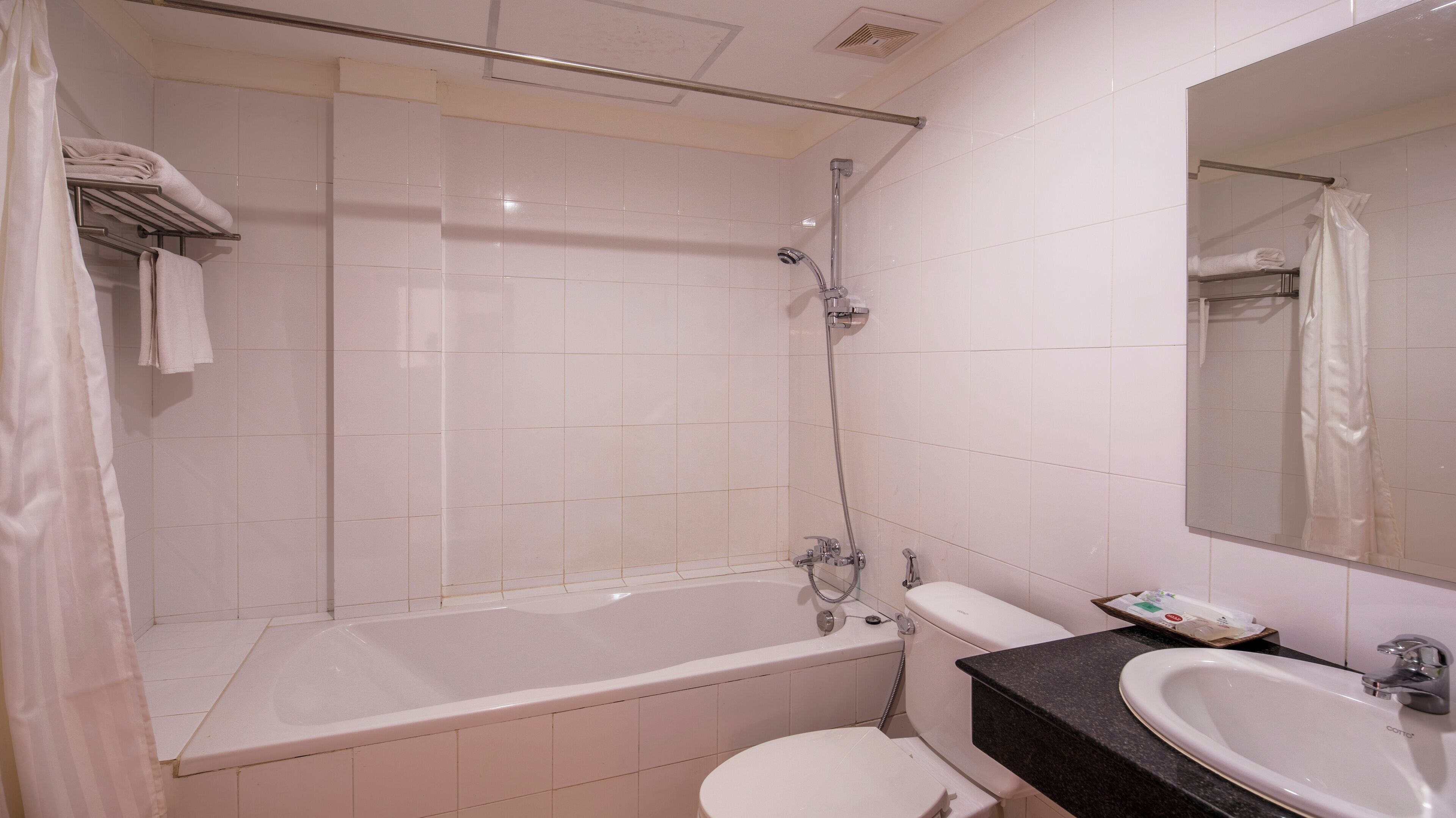A bathroom with a bathtub, toilet, sink, and a mirror.