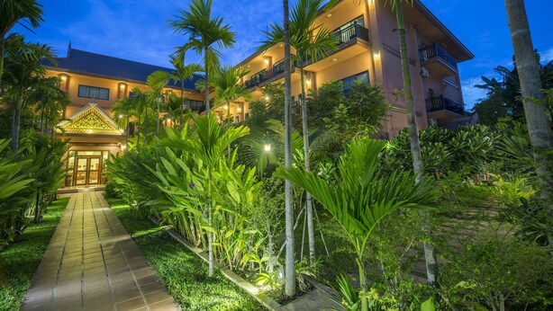 A multi-story hotel with a well-maintained garden pathway leading to the entrance. - Kouprey Hotel (Siem Reap)