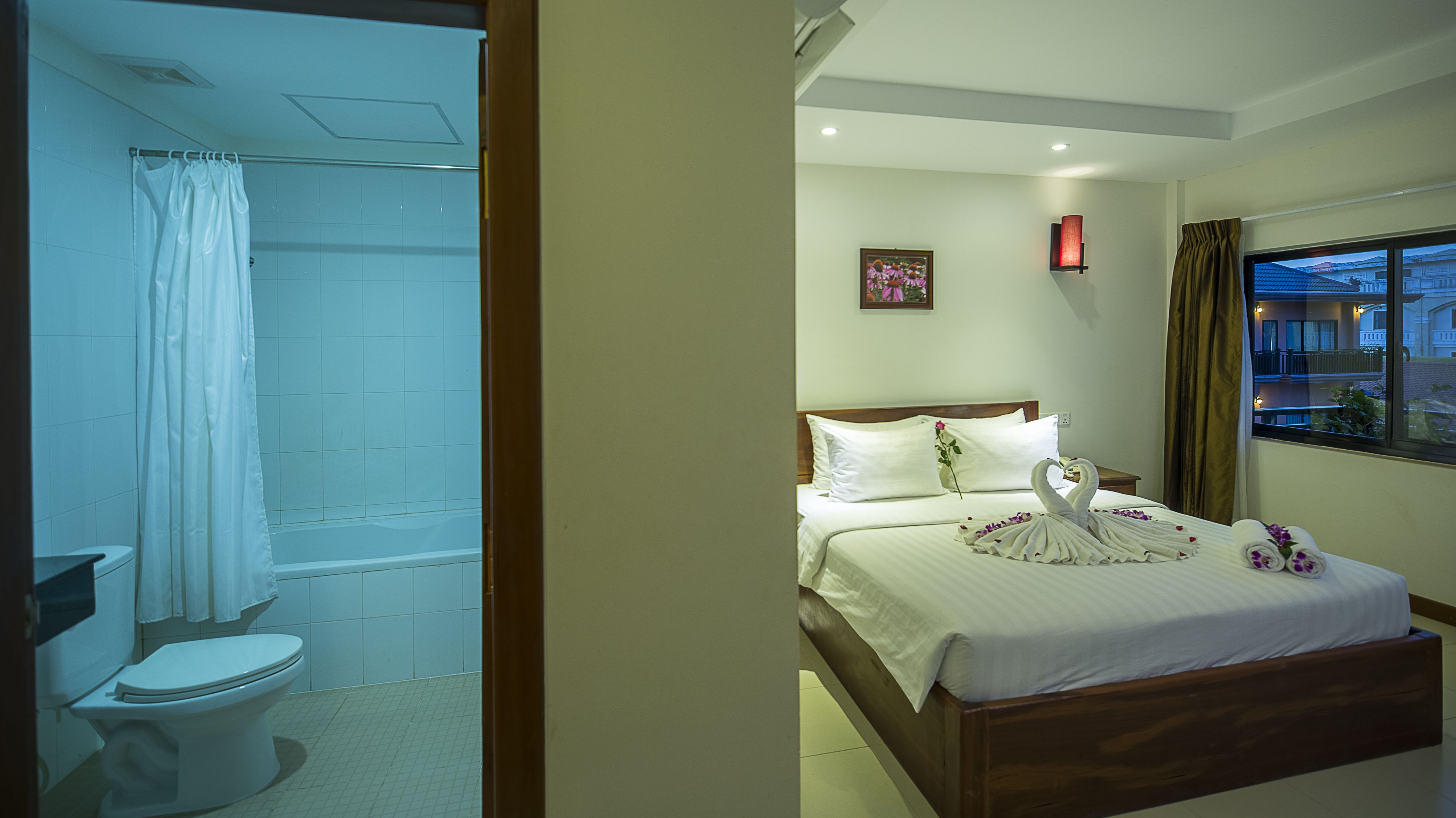 Habitación de hotel con cama, ducha y vistas al exterior.