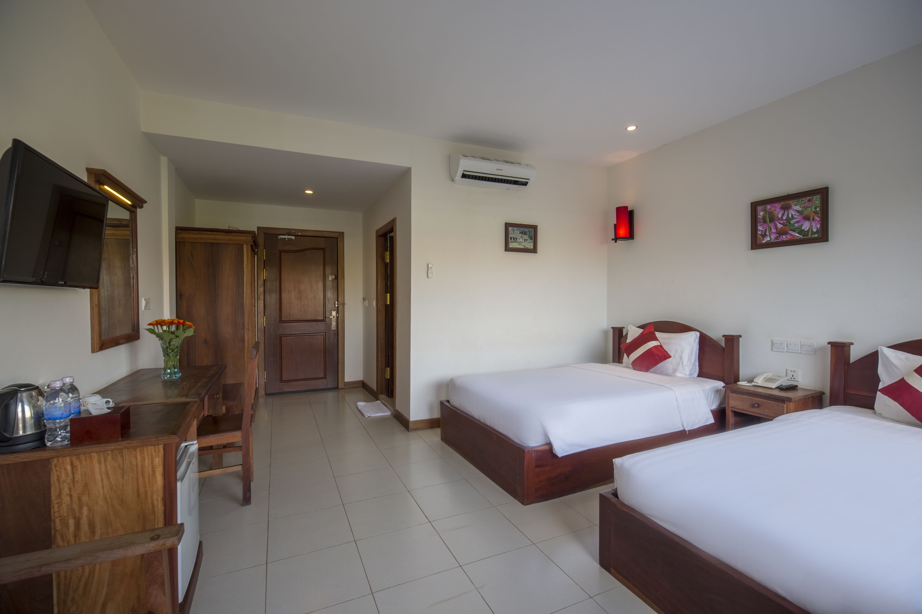 Une chambre d’hôtel avec deux lits, un bureau avec une chaise, une télévision et un appareil de climatisation.