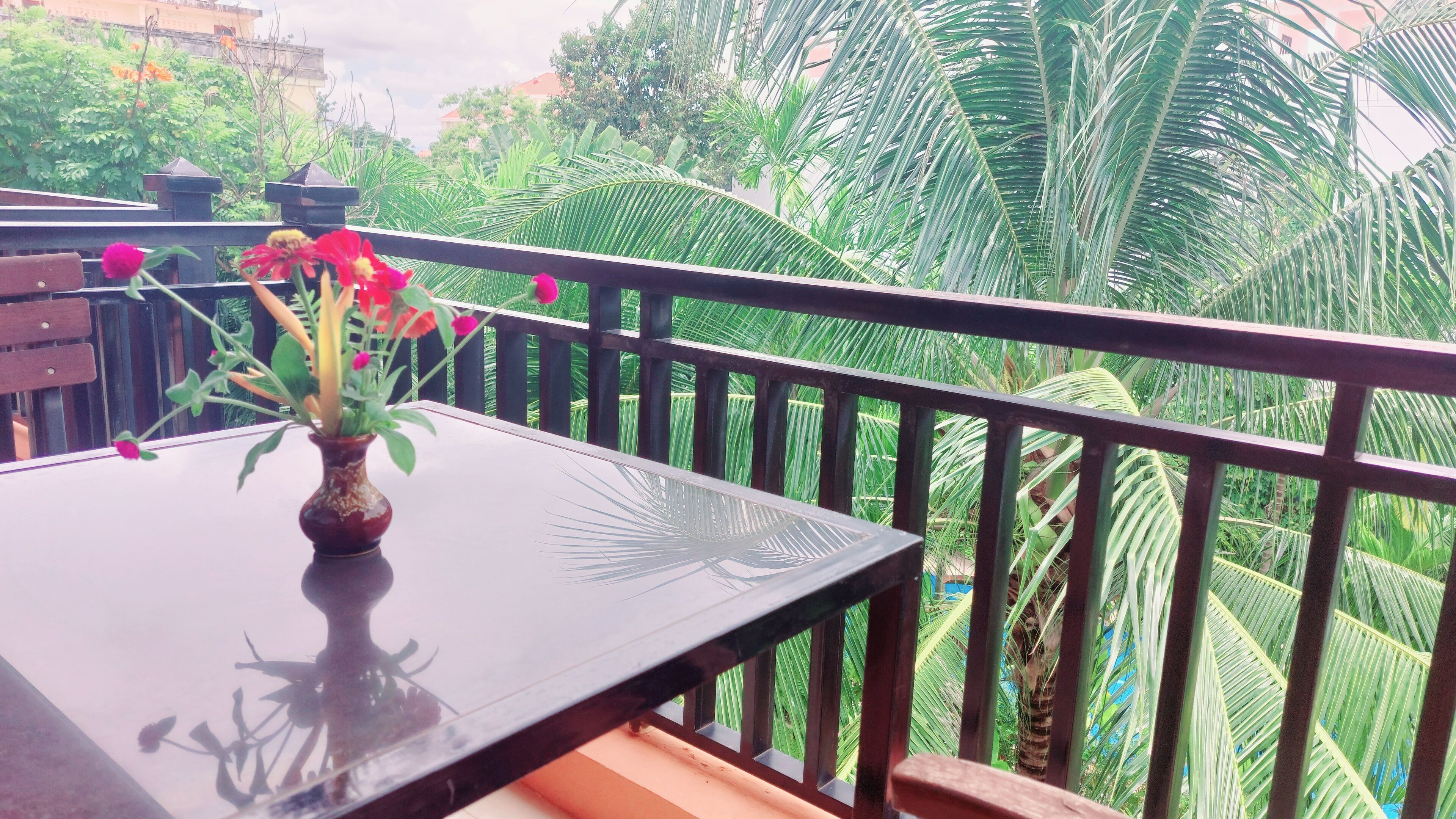 A balcony with a table and a vase of flowers.