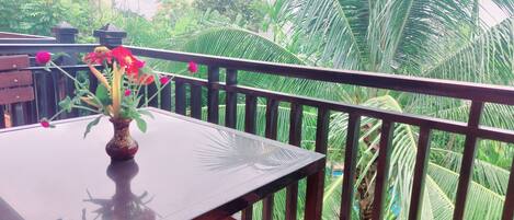 A balcony with a table and a vase of flowers.
