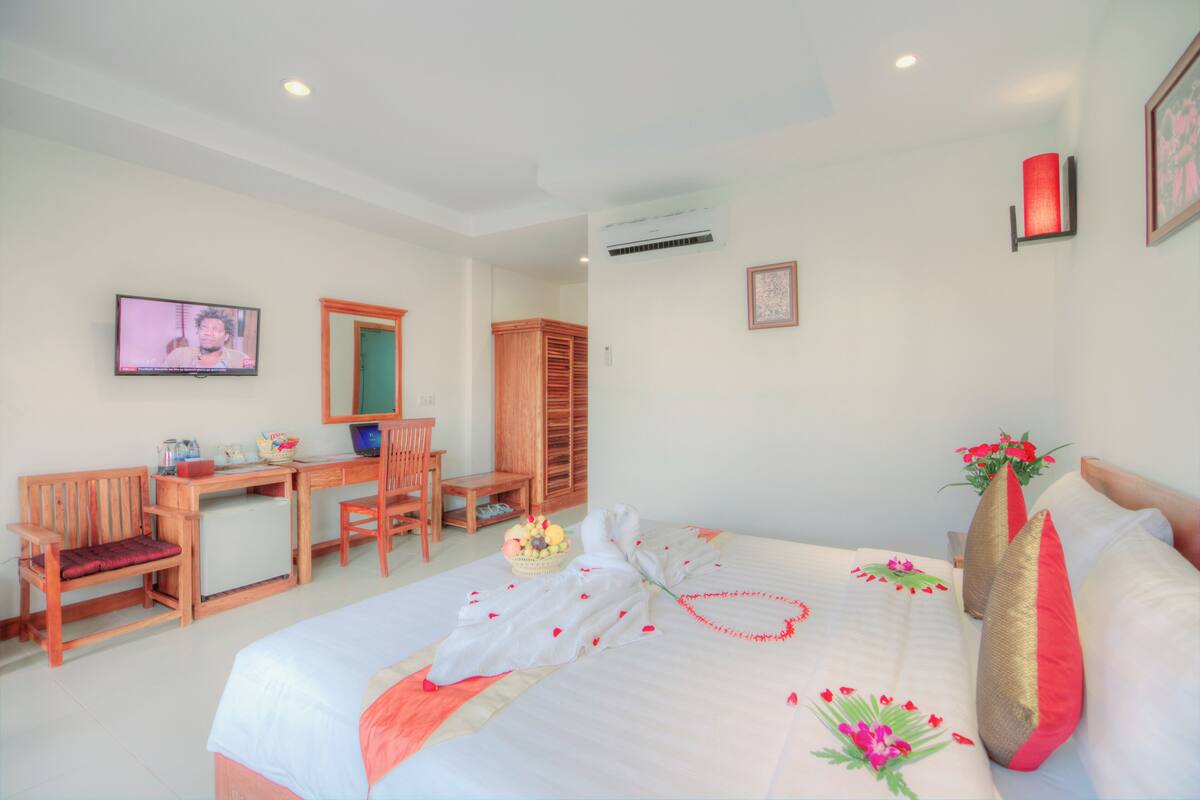 A hotel room with a bed, a desk, a chair, and a television.