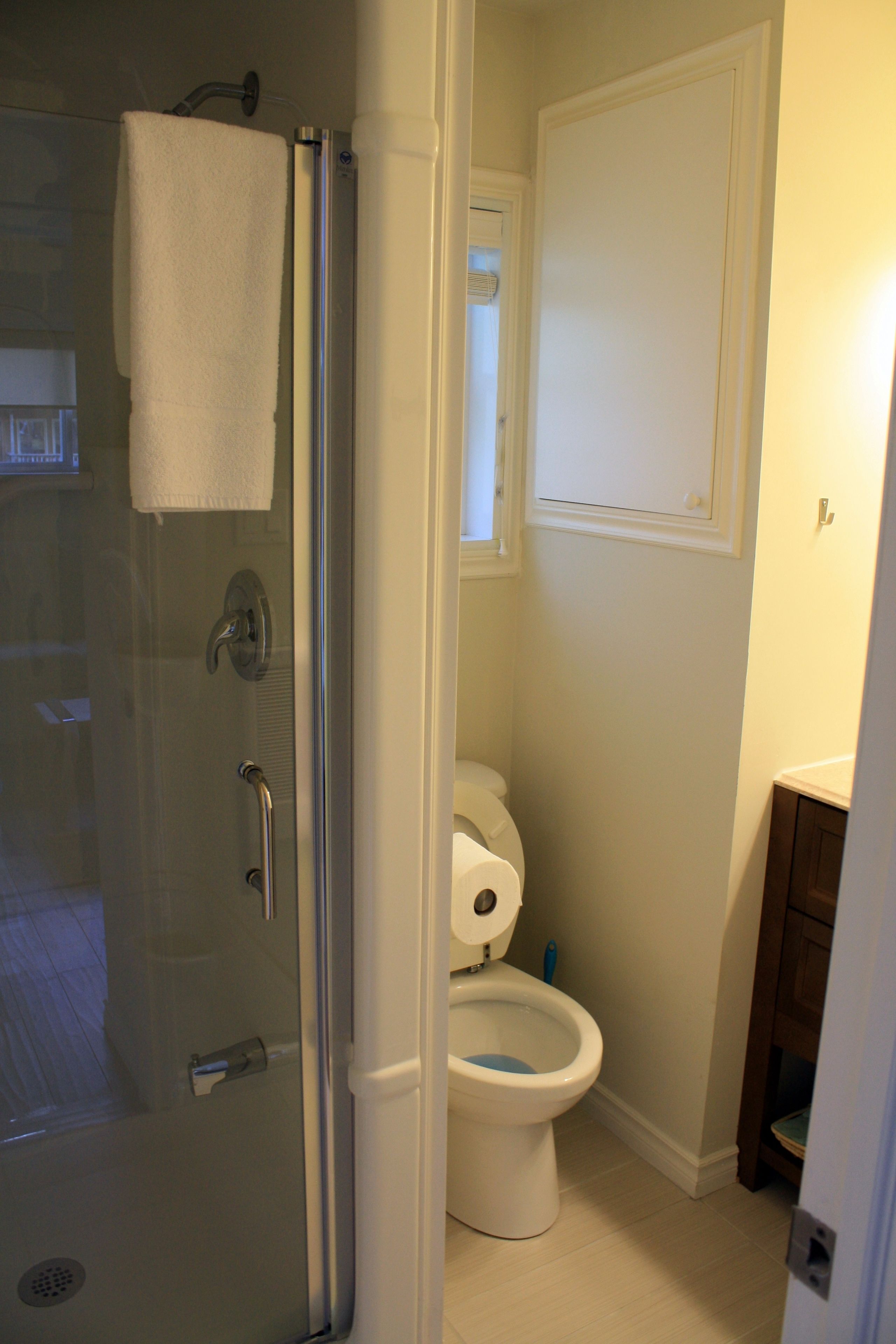 A bathroom with a glass shower enclosure, a toilet, and a sink.