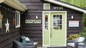 A rustic cabin with a green door labeled "OGOPOGO OFFICE" and a "WELCOME" sign. - Ogopogo Resort (Minden Hills)