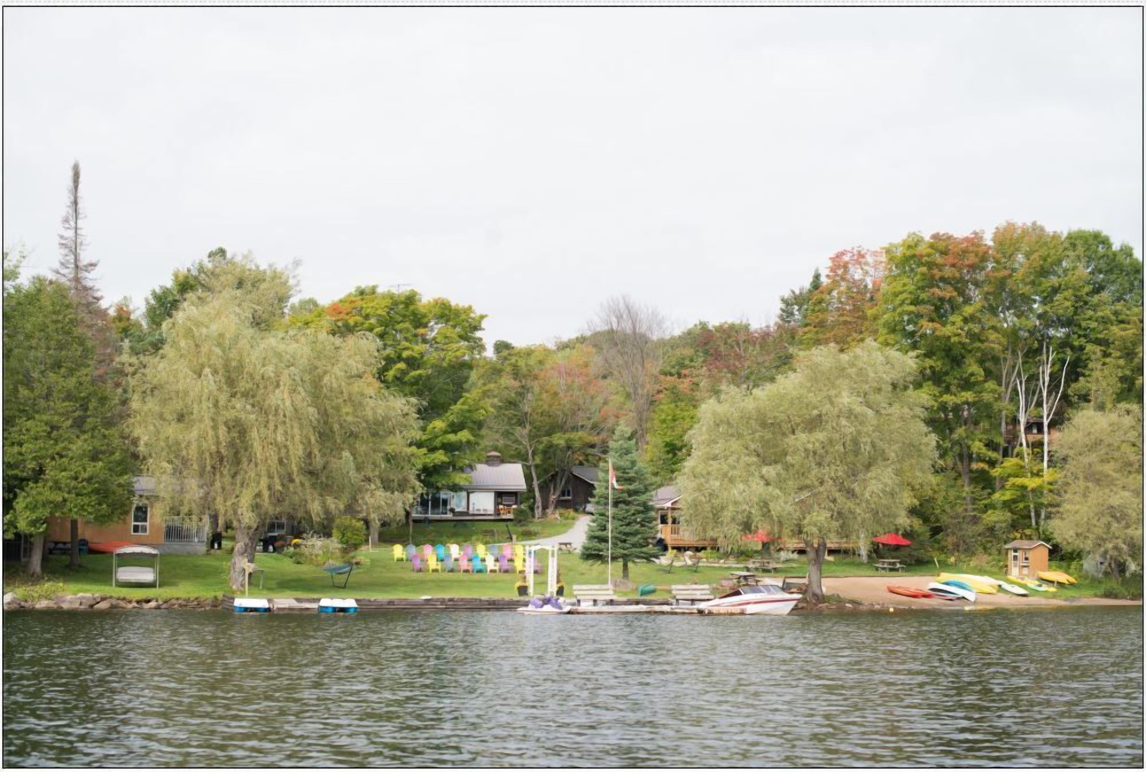 A lakeside property with a dock, boats, and a small cabin.