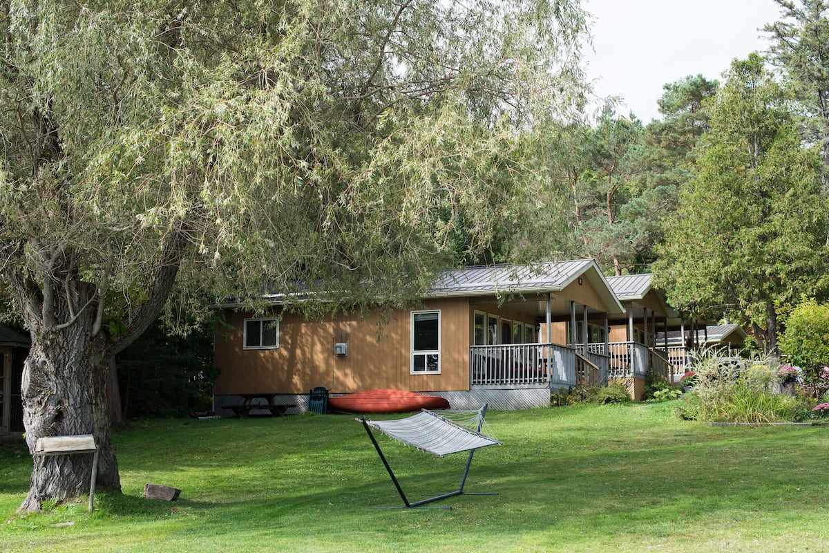 A house with a porch, a hammock, and a boat in the yard.