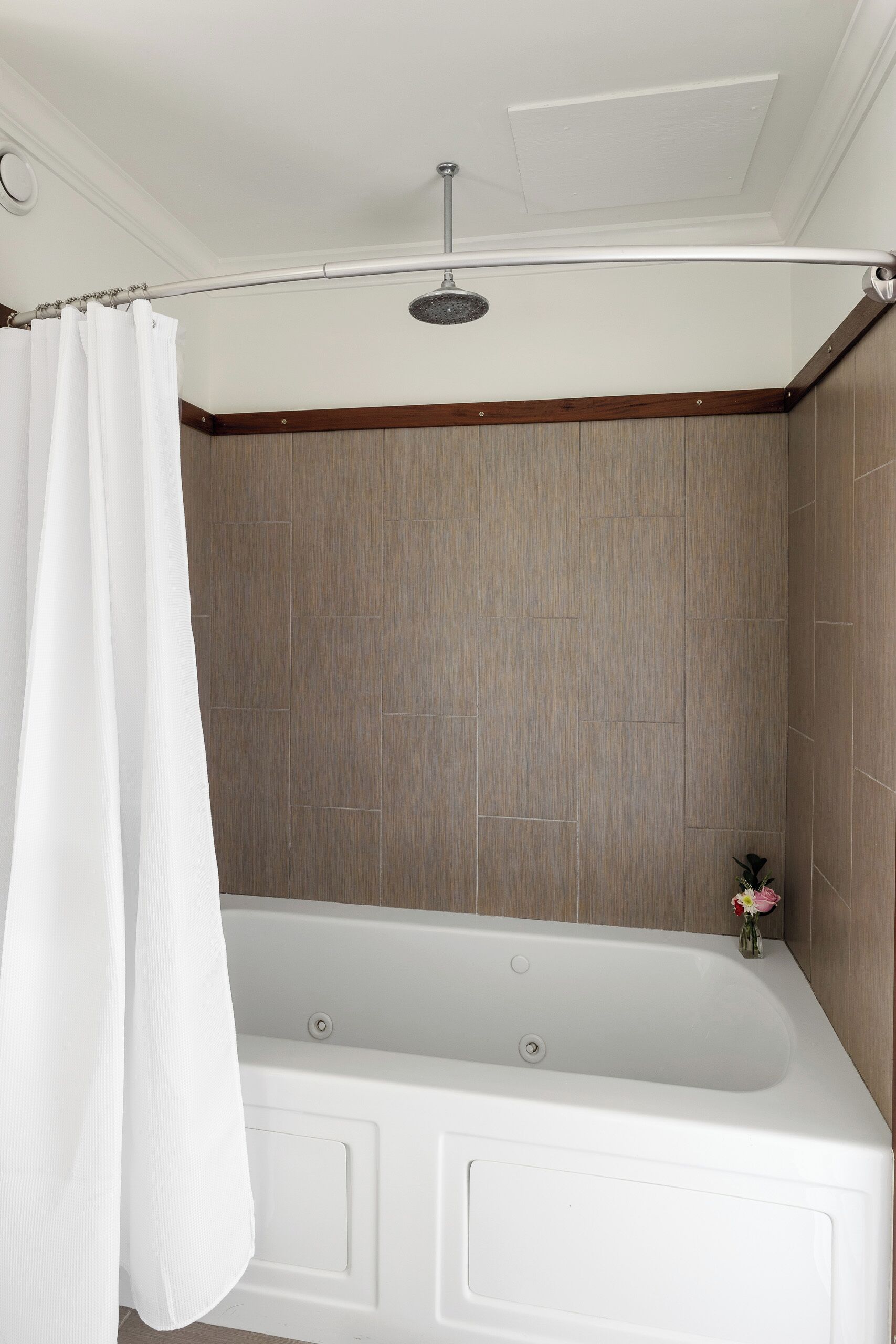 Une salle de bain avec une baignoire, une douche et un rideau blanc.