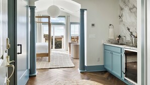 A modern kitchen with blue cabinets, a marble backsplash, and a large window overlooking a balcony.