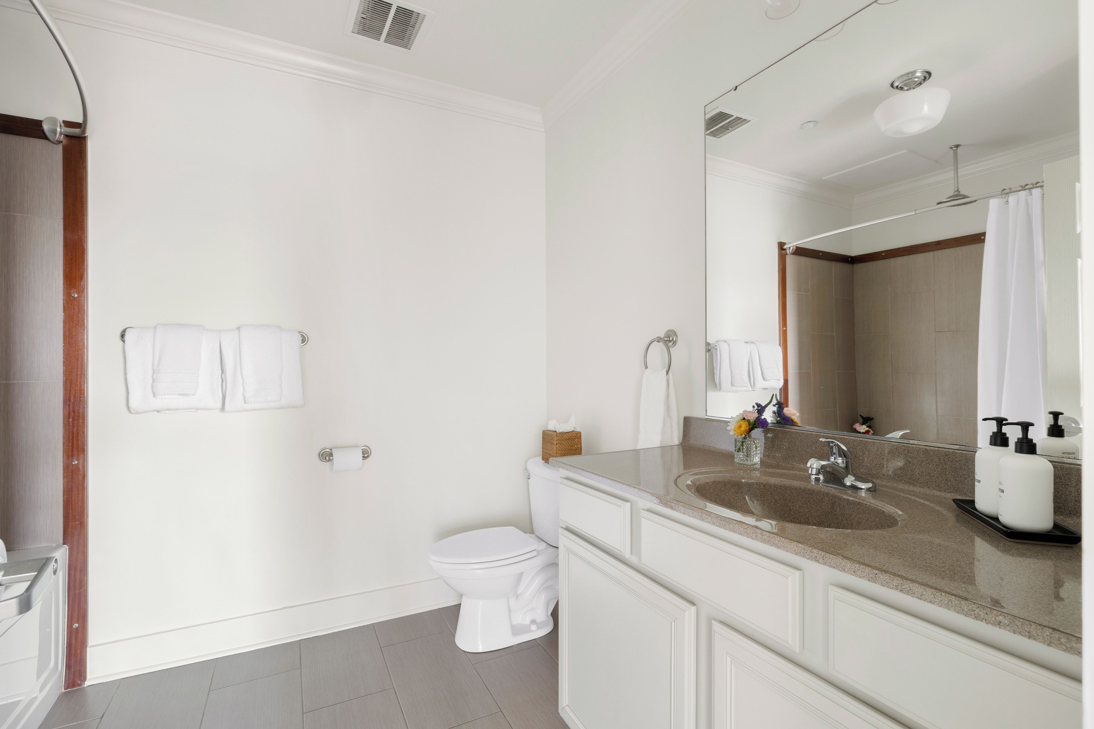 Un baño moderno con ducha, inodoro y tocador con lavabo y espejo.