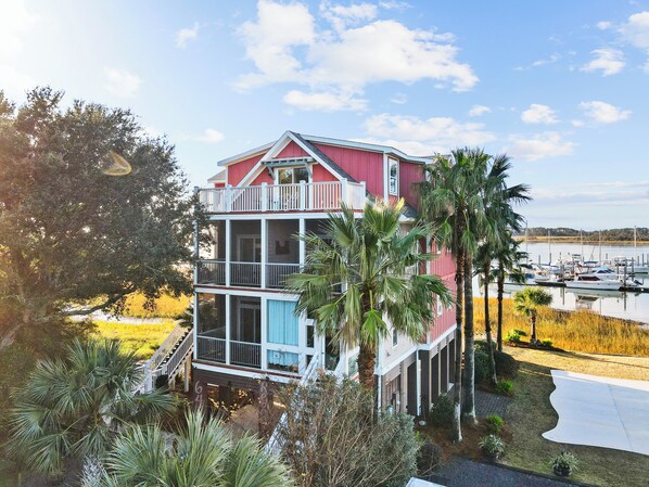 A multi-story house with a balcony, surrounded by palm trees and a marina. - Regatta Inn Folly Beach (Folly Beach)