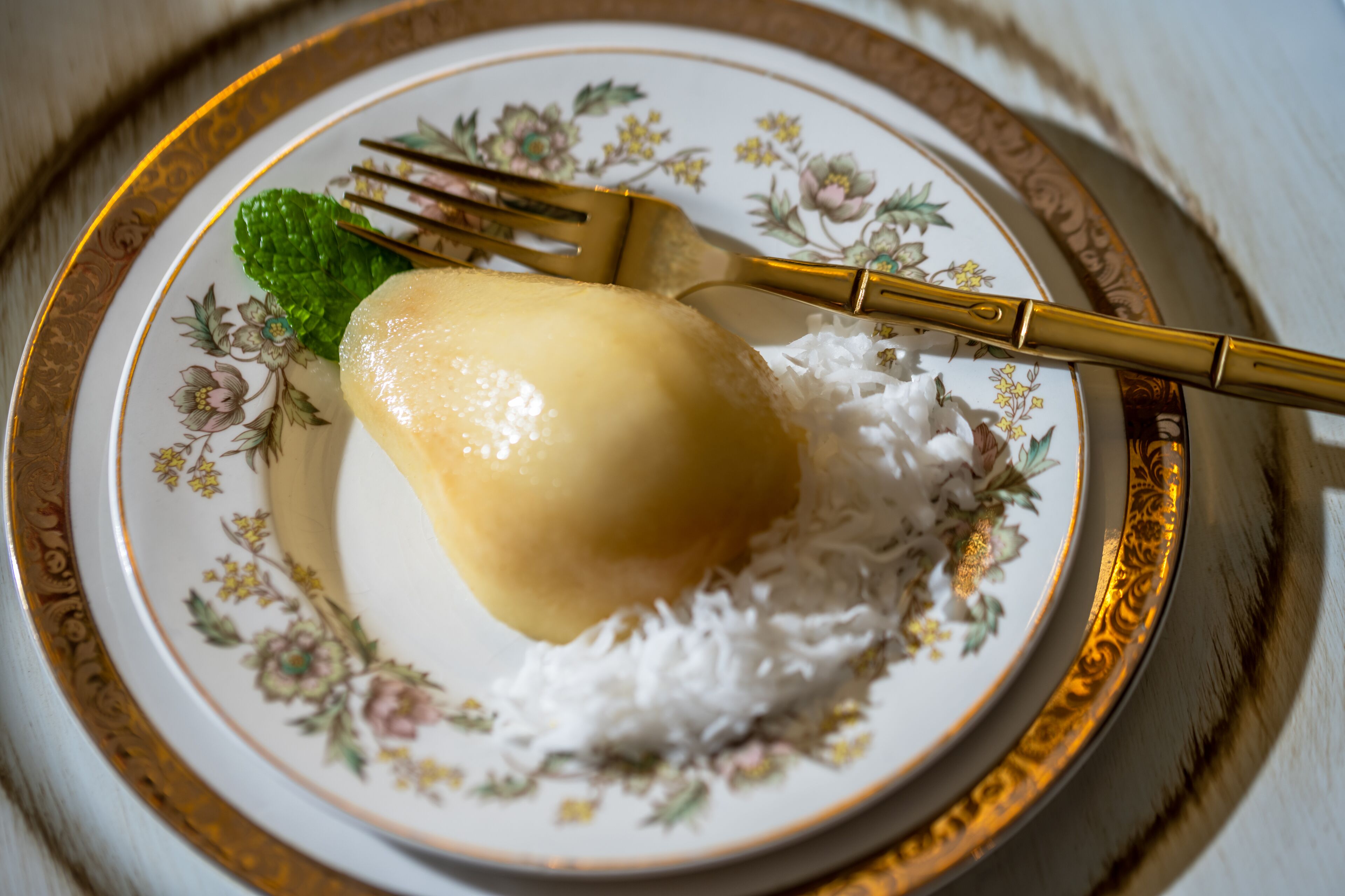 A plate with a dessert, possibly a pudding, on a floral-patterned plate with a gold rim.